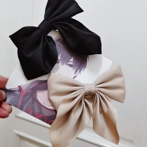 Detailed view of satin bow hair clips in black and champagne on a display card