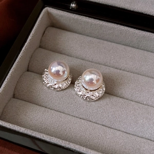 Close-up of vintage-style round pearl earrings with textured silver metal setting