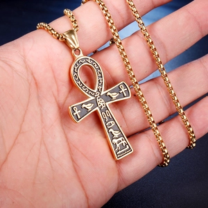 Detail of a gold-colored Egyptian Ankh cross pendant with hieroglyphic engravings on hand