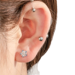 Snowflake zircon stud earrings in silver finish with blue and white gems on model's ear