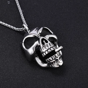 Macro shot of silver stainless steel skull pendant with cigarette and thick chain