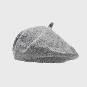 Detailed close-up of a grey chunky knit cotton beret with classic painter hat style texture