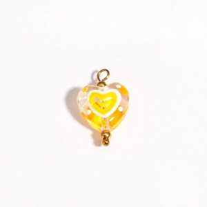 Detail of a handmade heart glass bead pendant in yellow with orange and white patterns