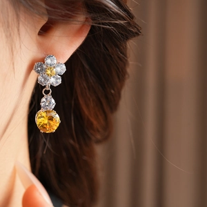 Detailed close-up of a zircon flower petal earring worn by a model in a warm setting