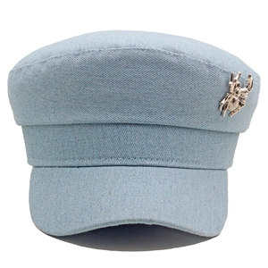Détail d'une casquette baker boy en denim bleu clair avec une broche araignée en métal argenté