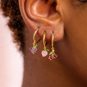 Macro shot of colorful zircon fruit earrings including grape, heart and cherry charms