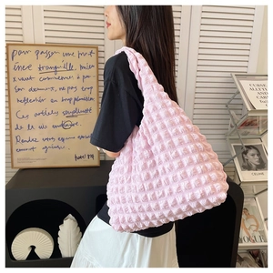 Close-up of pink pleated cloud bag with unique bubble texture and woven shoulder strap