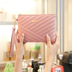 Close-up of pink quilted leather wristlet bag with gold zipper and wrist strap detail