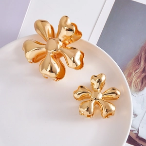 Golden flower metal hair claw clips set in two sizes on a white decorative plate