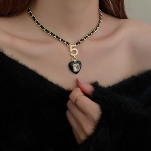 Detail of luxury gold and black leather chain necklace with number 5 and heart pendant