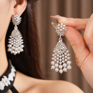 Detail of silver drop earrings with pearls and rhinestones on model's ear