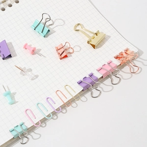 Macaron stationery set with binder clips and paperclips on white grid notebook