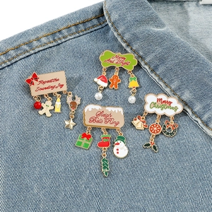 Christmas themed enamel brooch pins with festive pendants on blue denim background
