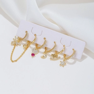 Goldenes Ohrring-Set mit Schmetterlings-, Herz-, Mond- und Sternanhängern auf weißer Seide