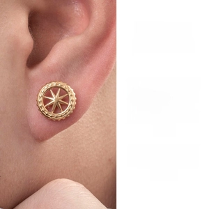 Macro detail of a golden starburst earring on ear showcasing vintage ethnic style