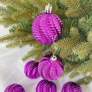 Nahaufnahme einer glänzenden lila Weihnachtskugel mit Spiralmuster am Tannenbaum