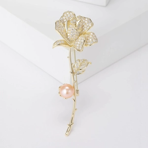 Détail d'une broche rose avec zircons étincelants et perle rose sur un présentoir blanc