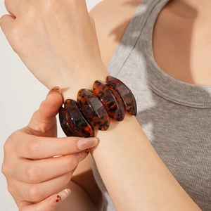 Close-up of tortoise shell resin bangle featuring retro brown leopard pattern on model