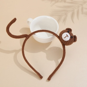 Cute brown knitted headband featuring handmade bear and tail on beige background