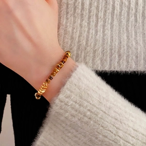 Retro Tiger Eye stone bracelet with gold metal accents on a model wearing a white sweater