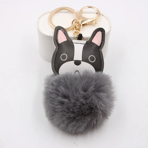 Detail of bulldog leather keychain with a fluffy grey pompom and gold lobster clasp