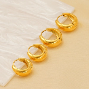 Polished gold-plated thick hoop earrings in four sizes on a warm minimalist background