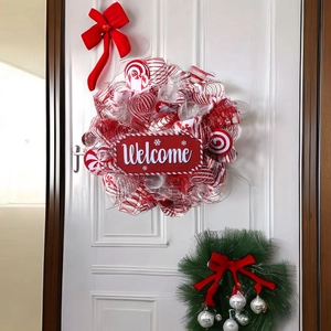 Red and white candy cane Christmas wreath with Welcome sign on a white front door