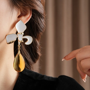 Detailansicht von Vintage-Blumenohrringen mit goldenem Tropfenanhänger am Modell