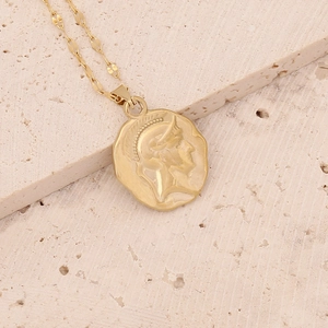 Detail of gold-tone irregular round medallion pendant with embossed portrait on stone