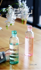 Detail view of pink and green glass bottles with time markers on a wooden table