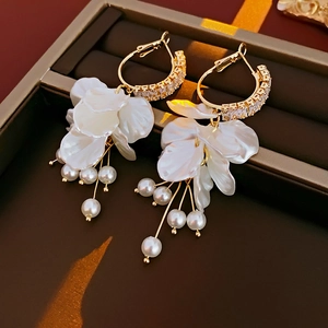 Detail of gold flower petal earrings with hanging pearls and zircon on display