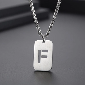 Vue macro d'un collier en acier titane argenté avec pendentif lettre F sur une chaîne torsadée