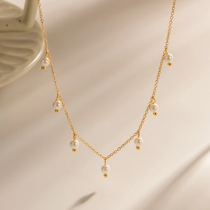 Elegant gold-plated necklace with seven round white pearls on a fine stainless steel chain