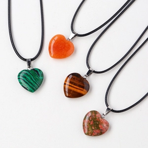 Flat lay of four 20mm natural stone heart pendants in malachite, agate, and tiger eye