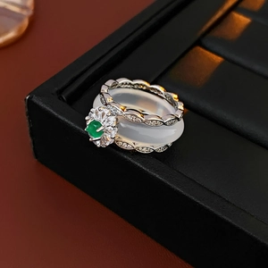 Close-up of vintage silver ring featuring a green emerald-style stone and hollow carvings