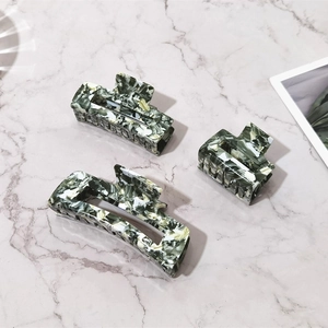 Three-piece acetate hair claw set featuring dark green marble patterns on a stone surface