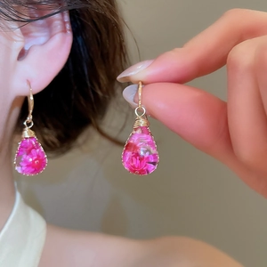 Close-up detail of handmade resin teardrop earrings featuring delicate pink dried flowers.