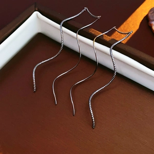 Gros plan de boucles d'oreilles noires en forme de vague sur un plateau élégant