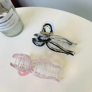 Detail of pink and black-trimmed transparent acrylic hair claws with metal spring
