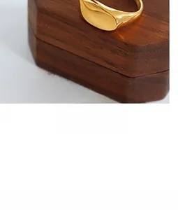 Close-up of irregular gold ring with a wavy design displayed on a brown wooden box