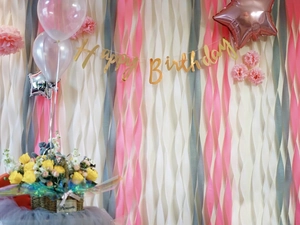 Detail of happy birthday banner with pink crepe paper streamers and party balloons