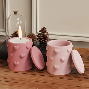 Detail of two pink heart embossed silicone candle jars with textured 3D patterns and lids