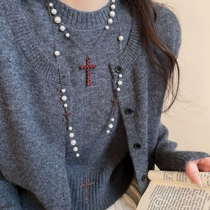 Detail einer mehrlagigen Perlenkette mit roten Strass-Kreuz-Anhängern