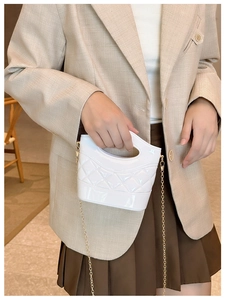 Dettaglio della mini borsa a secchiello bianca trapuntata lucida con catena dorata