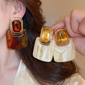 Close-up of geometric square resin earrings with faux gemstone and gold metal frame