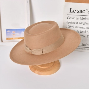 Detail of a beige wool felt fedora hat featuring a silk ribbon and bow on a wooden stand