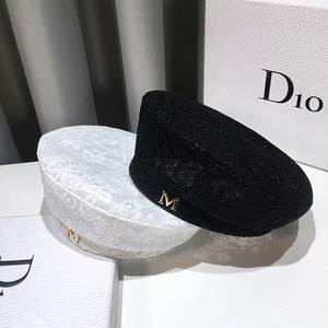 Close-up of black and white lace beret hats with floral patterns and a metal M charm