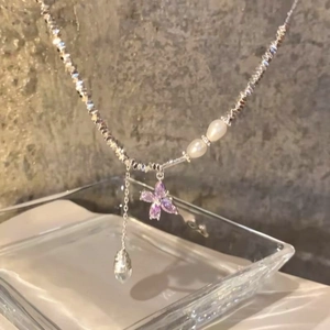 Vista dettagliata di una collana in argento con farfalla di zircone viola e perle.