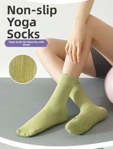 Detailed view of non-slip silicone grips on light green mid-tube yoga socks with ruffle trim