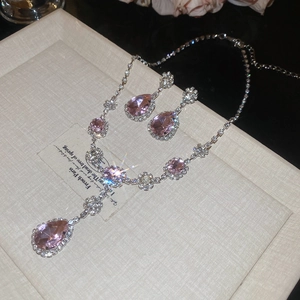 Dettaglio macro della collana e orecchini in argento con pietre rosa a forma di pera